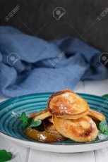 Pancakes with caramelized pear and tea with lemon and mint. Selective focus. Wooden white background. Top view