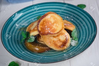 Pancakes with caramelized pear and tea with lemon and mint. Selective focus. Wooden white background. Top view