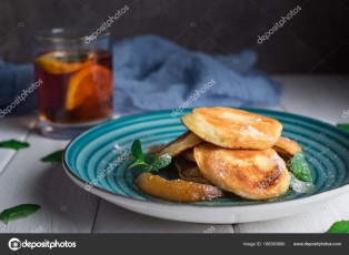 Pancakes with caramelized pear and tea with lemon and mint. Selective focus. Wooden white background. Top view