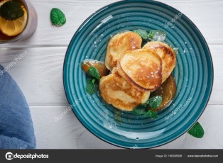 Pancakes with caramelized pear and tea with lemon and mint. Selective focus. Wooden white background. Top view