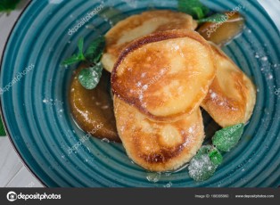 Pancakes with caramelized pear and tea with lemon and mint. Selective focus. Wooden white background. Top view