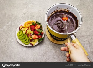 Chocolate fondue. Assorted fresh fruits, two types of chocolate, male hand. Ingredients for cooking a sweet romantic dessert. Stone concrete background